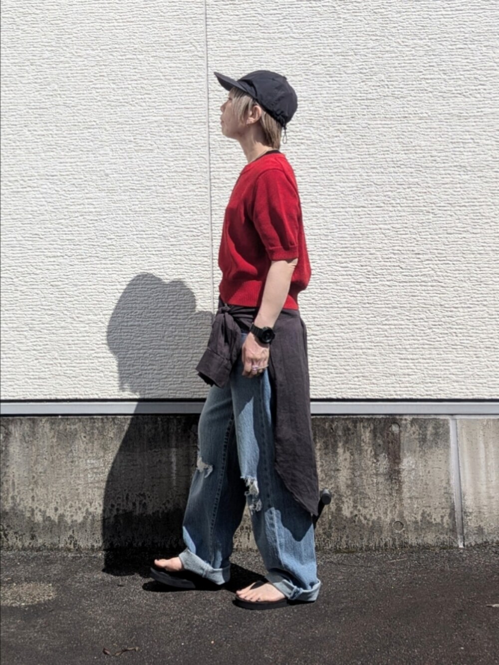 レッド系のニット/セーター、ブルー系のデニムパンツ、グレー系のシャツ/ブラウスを着用したレディースの夏コーディネートの2枚目の写真