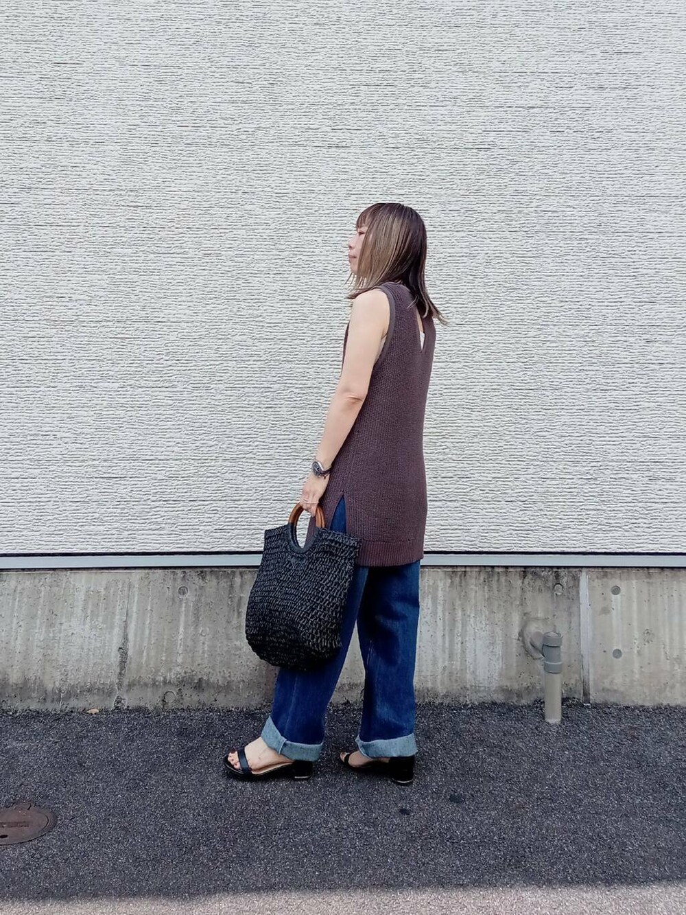 ブラック系のトートバッグ、ブルー系のデニムパンツ、ブラック系のニット/セーターを着用したレディースの夏コーディネートの3枚目の写真