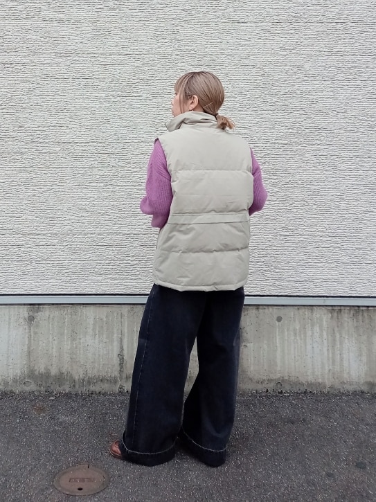 パープル系のニット/セーター、ベージュ系のダウンベスト、ブラック系のデニムパンツを着用したレディースの冬コーディネートの5枚目の写真