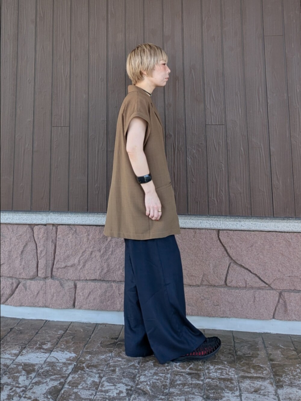 ブラウン系のダウンベスト、ブルー系のその他パンツ、ホワイト系のニット/セーターを着用したレディースの夏コーディネートの4枚目の写真