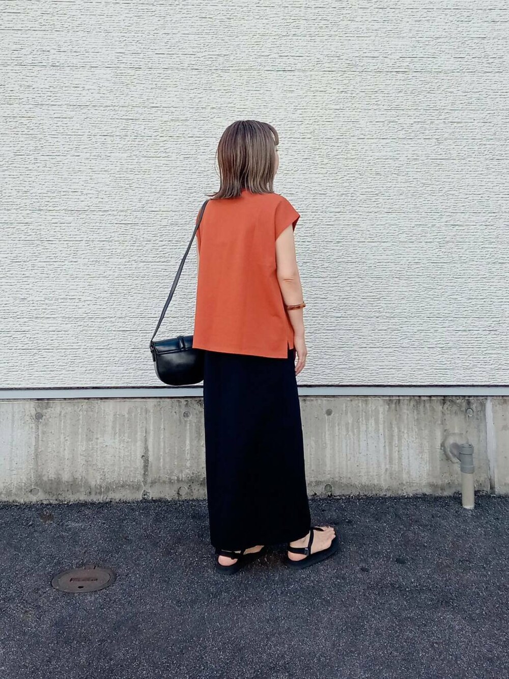オレンジ系のTシャツ/カットソー、ブラック系のショルダーバッグ、ブラック系のスカートを着用したレディースの夏コーディネートの5枚目の写真