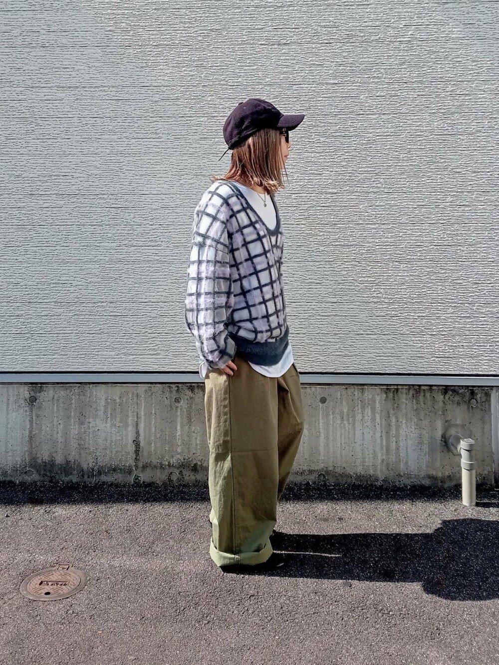 グレー系のニット/セーター、グリーン系のチノパンツ、ブラック系のメガネを着用したレディースの秋コーディネートの2枚目の写真