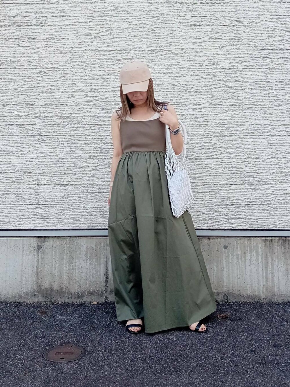 グリーン系のワンピース、ホワイト系のハンドバッグ、ベージュ系のキャップを着用したレディースの夏コーディネートの2枚目の写真