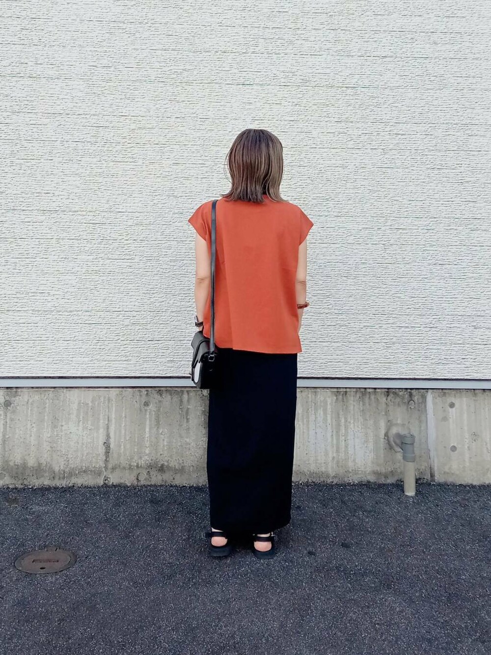 オレンジ系のTシャツ/カットソー、ブラック系のショルダーバッグ、ブラック系のスカートを着用したレディースの夏コーディネートの4枚目の写真