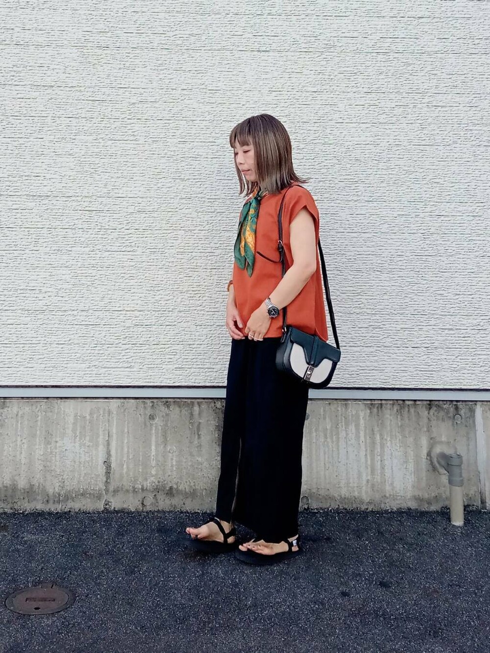 オレンジ系のTシャツ/カットソー、ブラック系のショルダーバッグ、ブラック系のスカートを着用したレディースの夏コーディネートの2枚目の写真