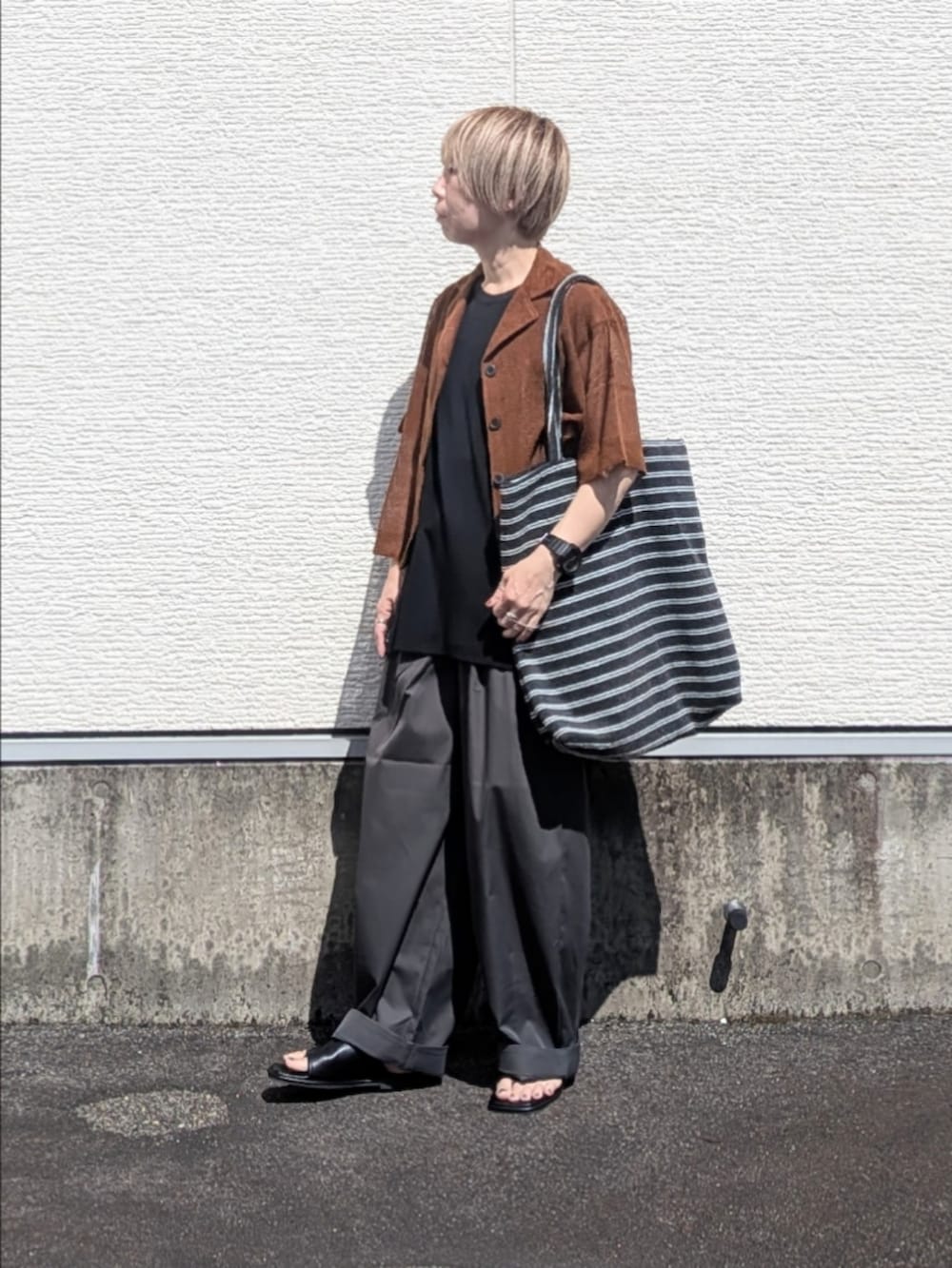 ブラック系のTシャツ/カットソー、グレー系のその他パンツ、ブラック系のサンダルを着用したレディースの夏コーディネートの5枚目の写真