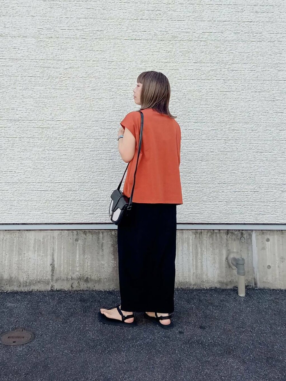 オレンジ系のTシャツ/カットソー、ブラック系のショルダーバッグ、ブラック系のスカートを着用したレディースの夏コーディネートの3枚目の写真