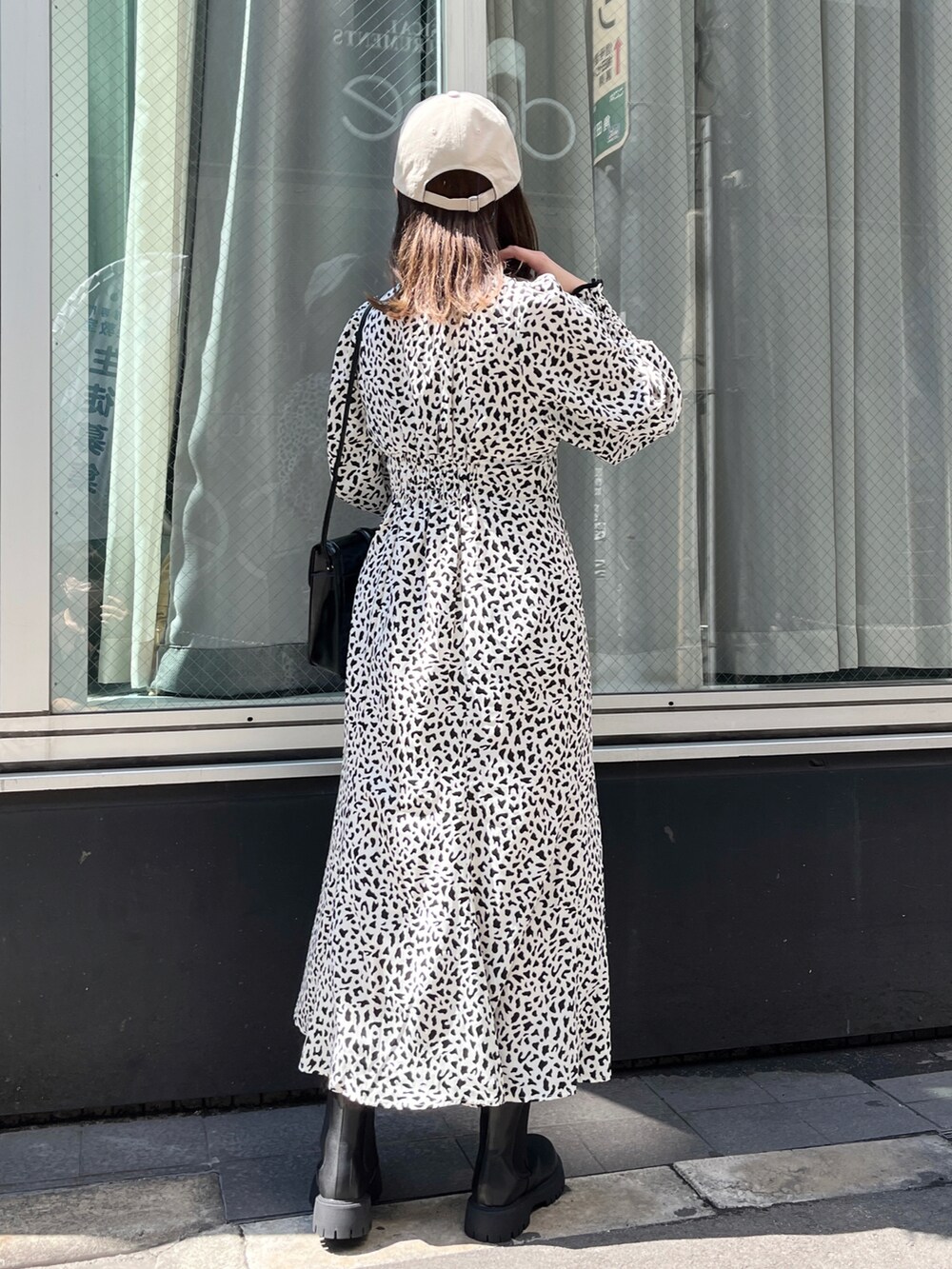 ホワイト系のワンピース、ブラック系のブーツ、ブラック系のショルダーバッグを着用したレディースの夏コーディネートの5枚目の写真