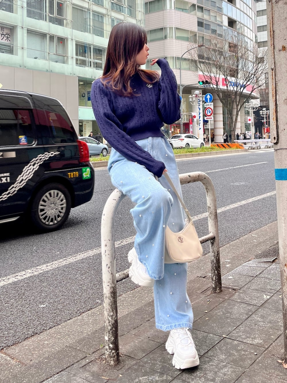 ブルー系のデニムパンツ、ホワイト系のショルダーバッグ、ホワイト系のスニーカーを着用したレディースの冬コーディネートの3枚目の写真