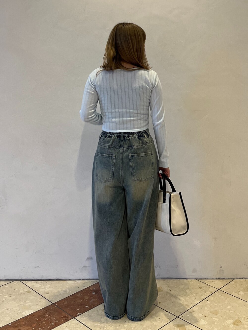 ブルー系のその他パンツ、ブラック系のスニーカー、ホワイト系のトートバッグを着用したレディースの冬コーディネートの6枚目の写真