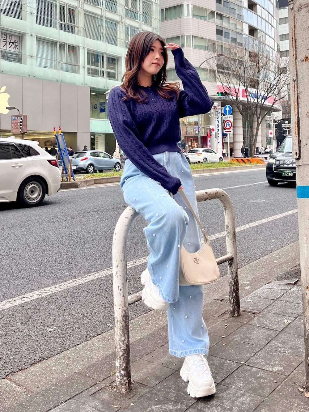 ブルー系のデニムパンツ、ホワイト系のショルダーバッグ、ホワイト系のスニーカーを着用したレディースの冬コーディネートの2枚目の写真