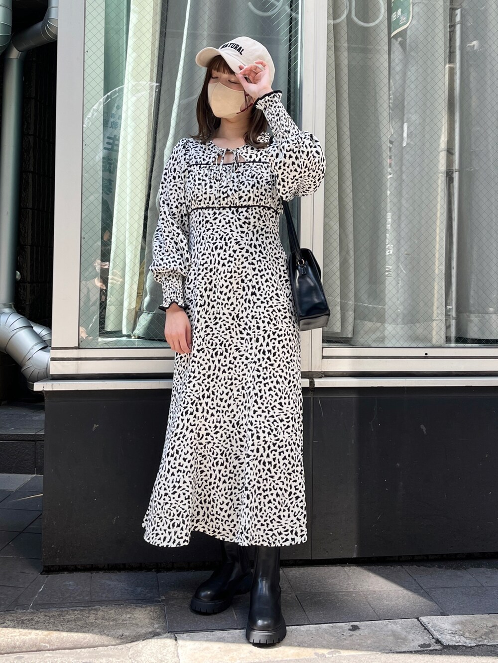 ホワイト系のワンピース、ブラック系のブーツ、ブラック系のショルダーバッグを着用したレディースの夏コーディネートの2枚目の写真