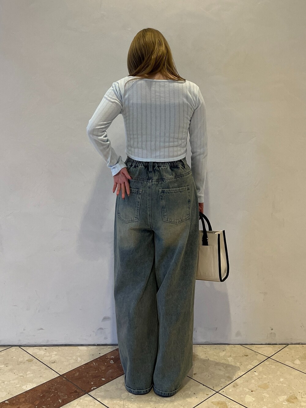 ブルー系のその他パンツ、ブラック系のスニーカー、ホワイト系のトートバッグを着用したレディースの冬コーディネートの3枚目の写真