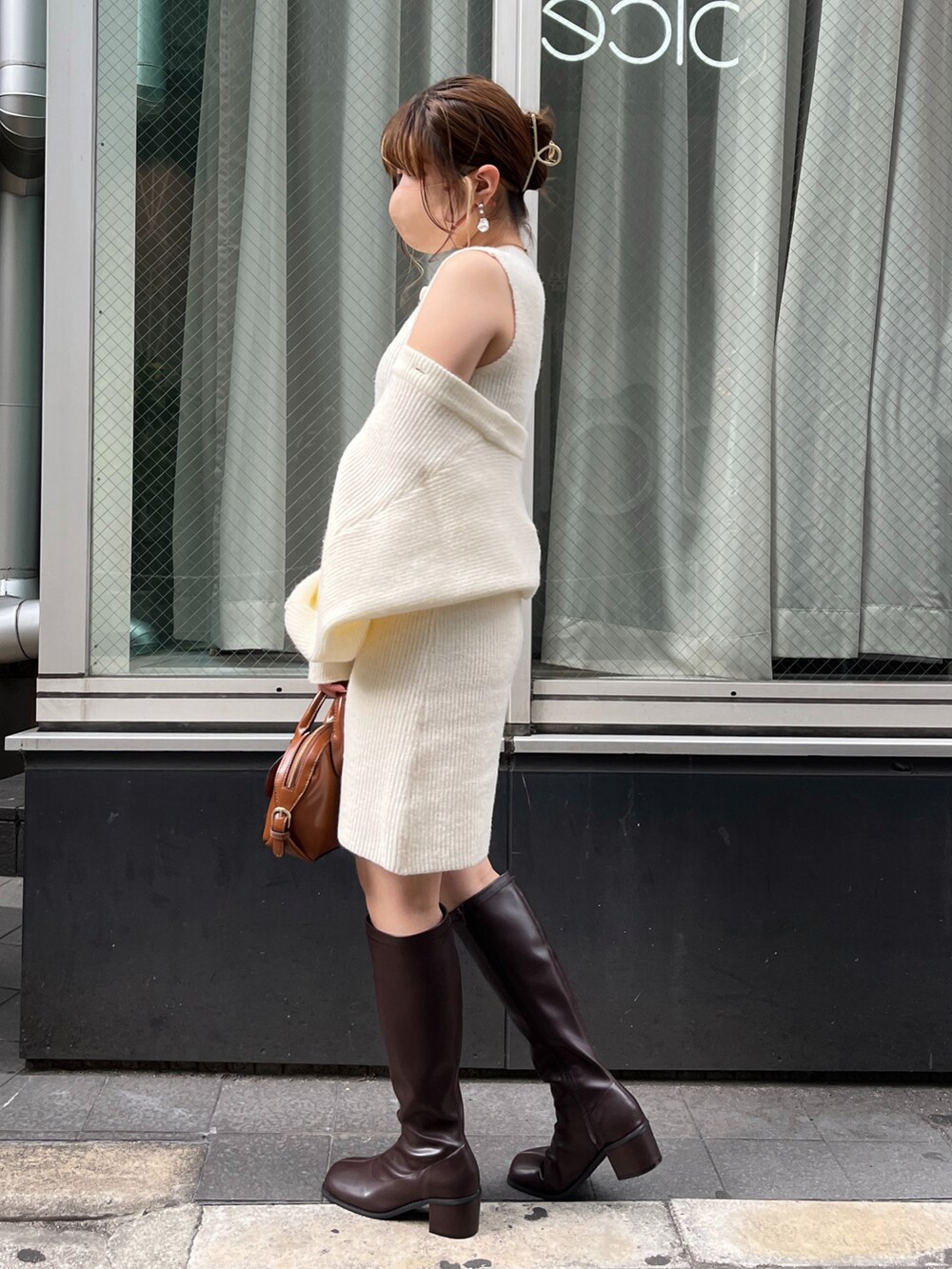 イエロー系のショルダーバッグ、ブラウン系のブーツ、ホワイト系のワンピースを着用したレディースの夏コーディネートの3枚目の写真