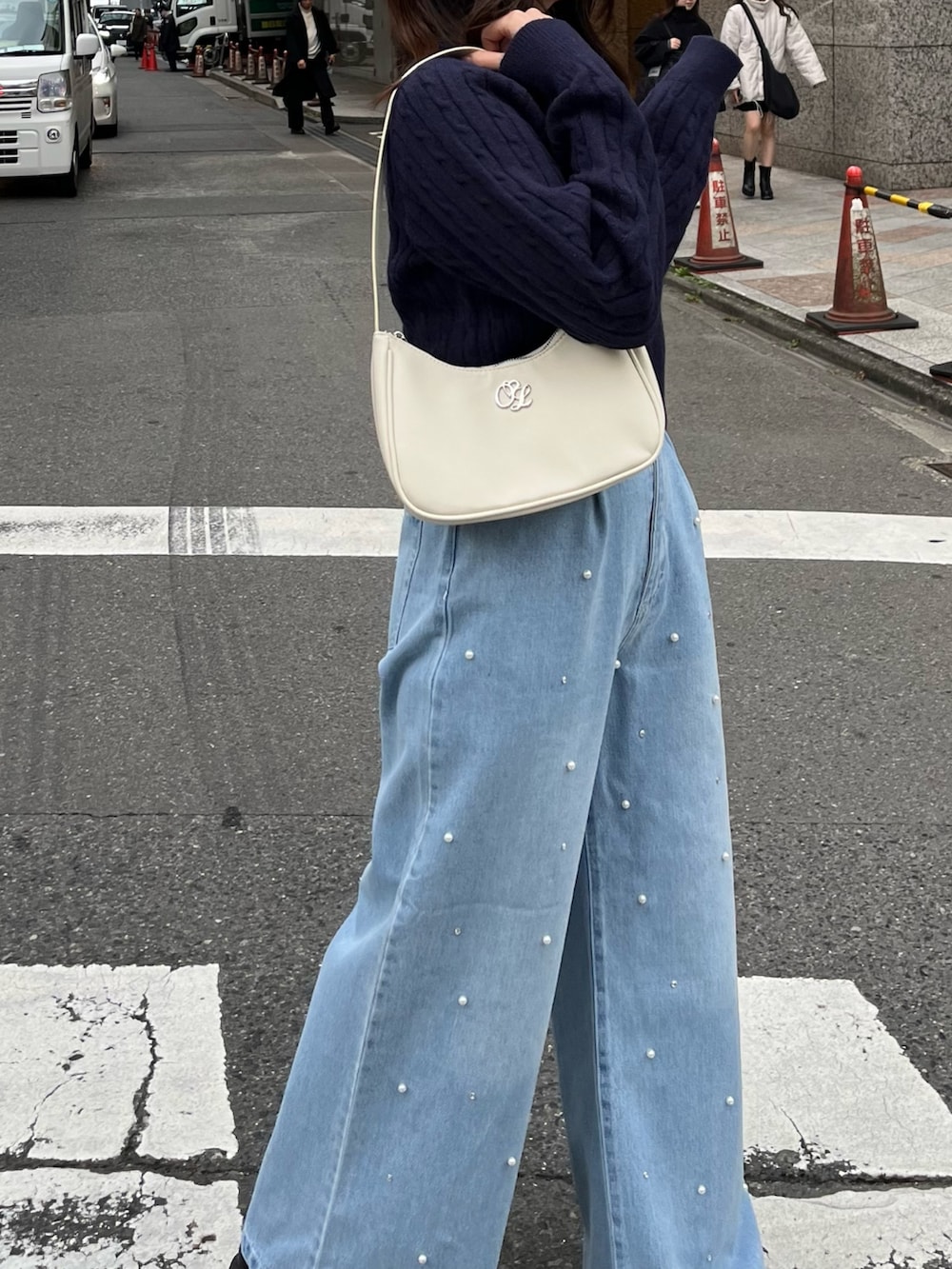 ブルー系のデニムパンツ、ホワイト系のショルダーバッグ、ホワイト系のスニーカーを着用したレディースの冬コーディネートの4枚目の写真