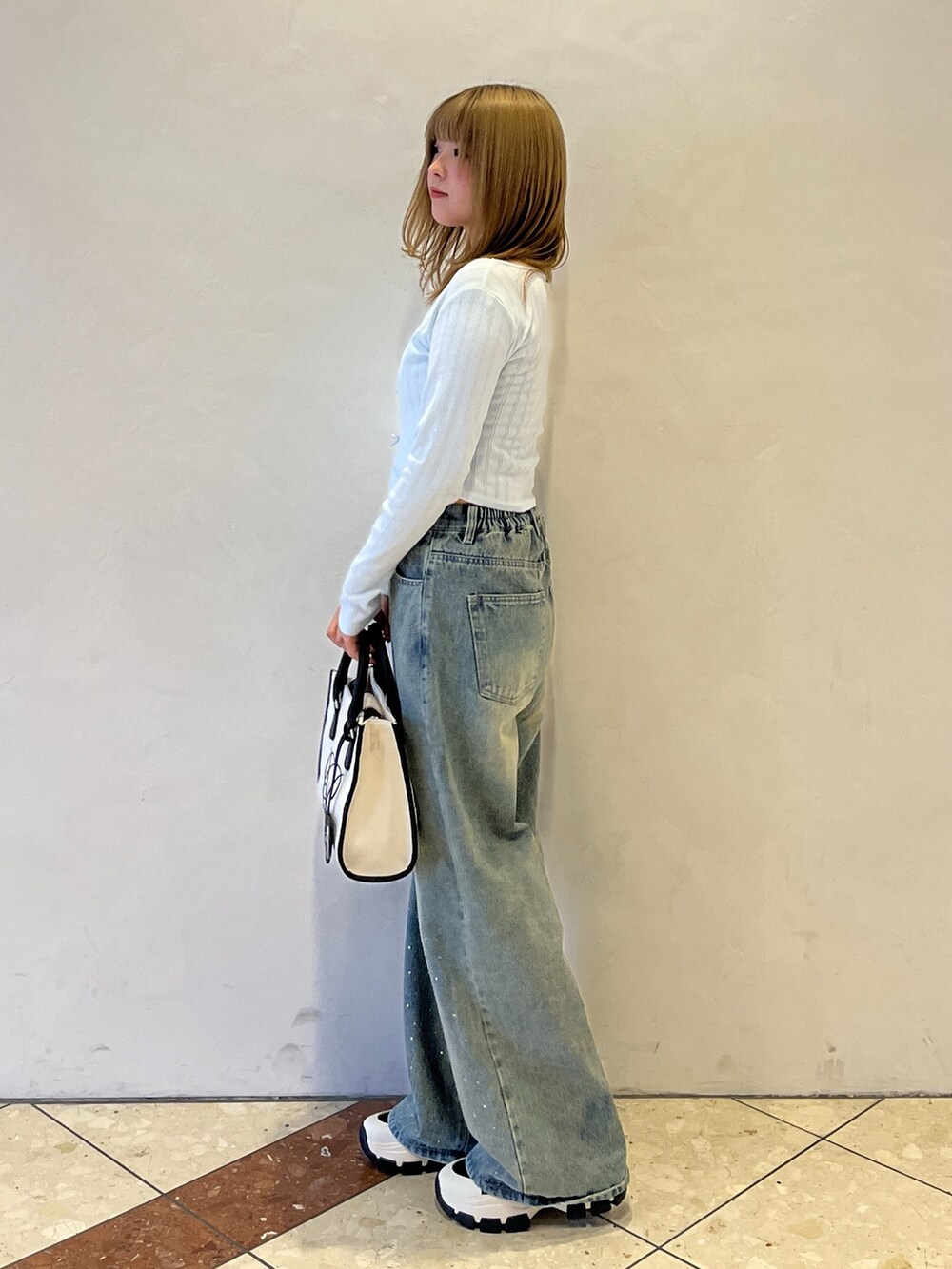 ブルー系のその他パンツ、ブラック系のスニーカー、ホワイト系のトートバッグを着用したレディースの冬コーディネートの2枚目の写真