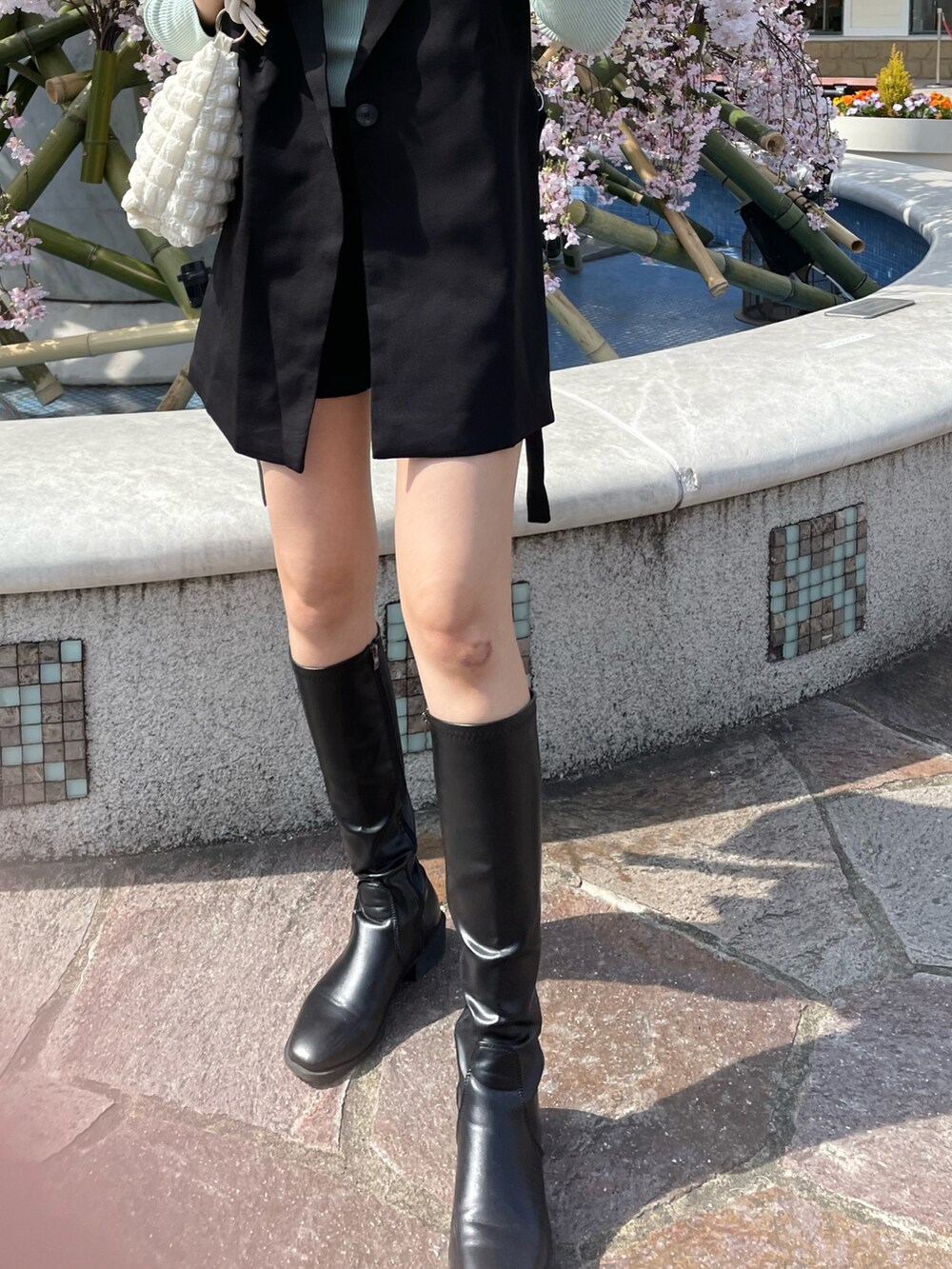 ブラック系のジャケット/アウター、グリーン系のニット/セーターを着用したレディースの春コーディネートの2枚目の写真