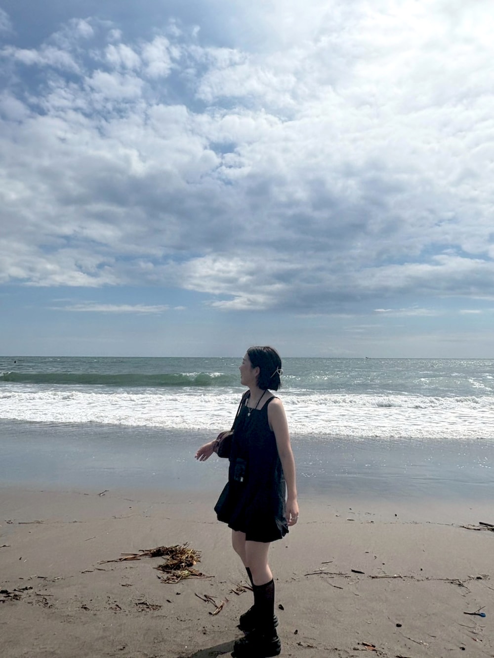 ブラック系のワンピース、ブラウン系のボストンバッグ、ブラック系のサンダルを着用したレディースの秋コーディネートの2枚目の写真