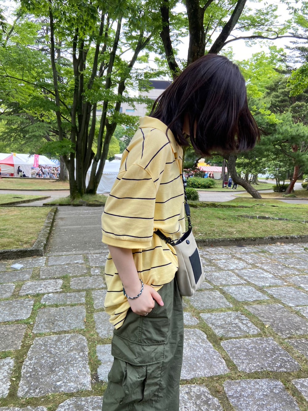グリーン系のカーゴパンツ、グリーン系のスニーカー、イエロー系のポロシャツを着用したレディースの夏コーディネートの2枚目の写真