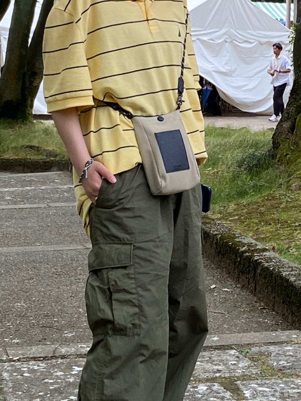 グリーン系のカーゴパンツ、グリーン系のスニーカー、イエロー系のポロシャツを着用したレディースの夏コーディネートの3枚目の写真