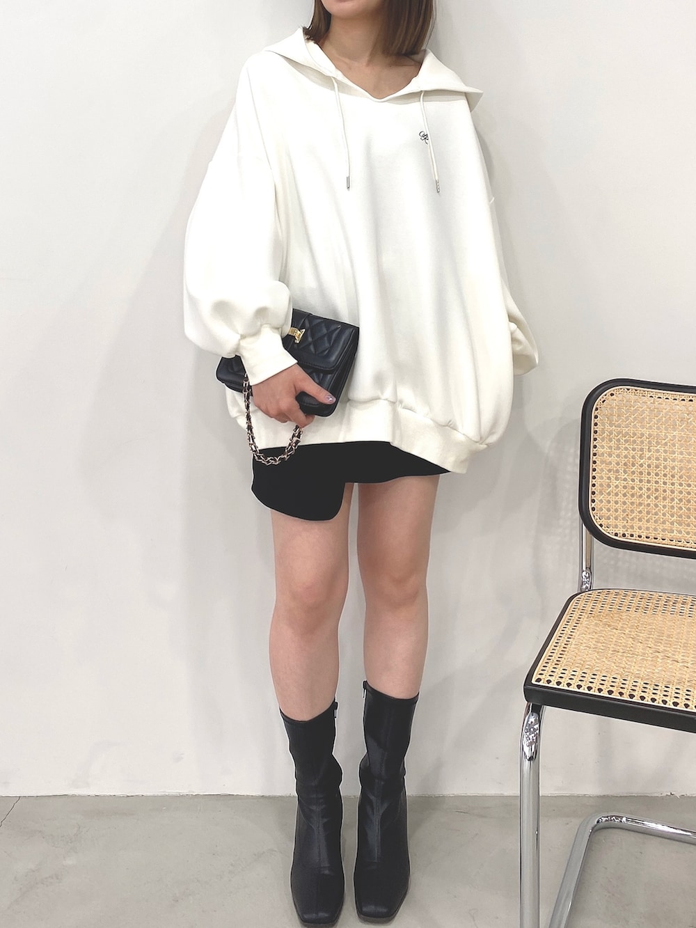 ホワイト系のパーカー、ブラック系のスカートを着用したレディースの秋コーディネートの3枚目の写真