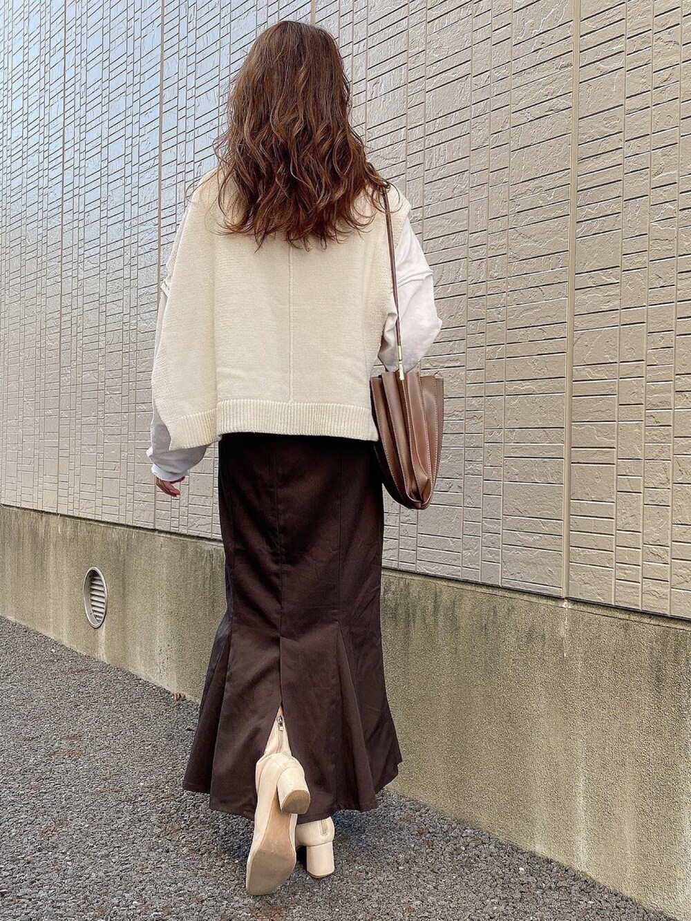 ブラウン系のスカート、ホワイト系のTシャツ/カットソー、ホワイト系のブーツを着用したレディースの冬コーディネートの2枚目の写真