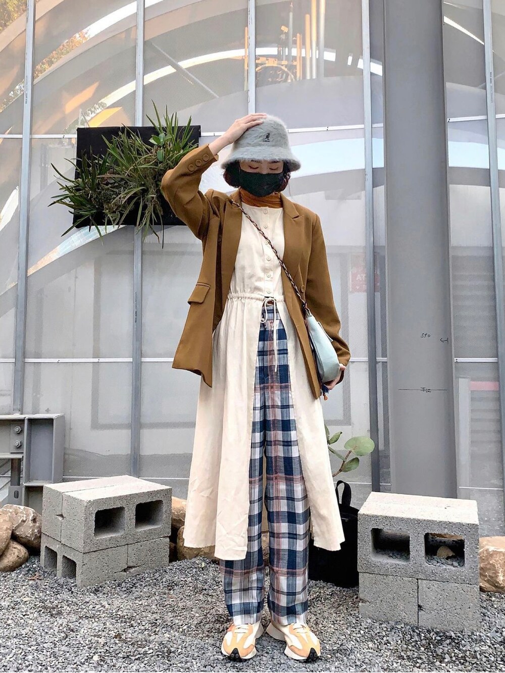 ベージュ系のベスト、ブルー系のショルダーバッグ、オレンジ系のスニーカーを着用したレディースの春コーディネートの2枚目の写真