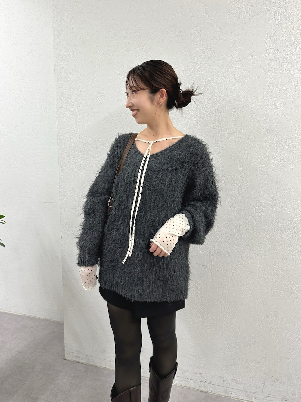 グレー系のニット/セーター、ホワイト系のTシャツ/カットソー、ブラウン系のブーツを着用したレディースの秋コーディネートの2枚目の写真