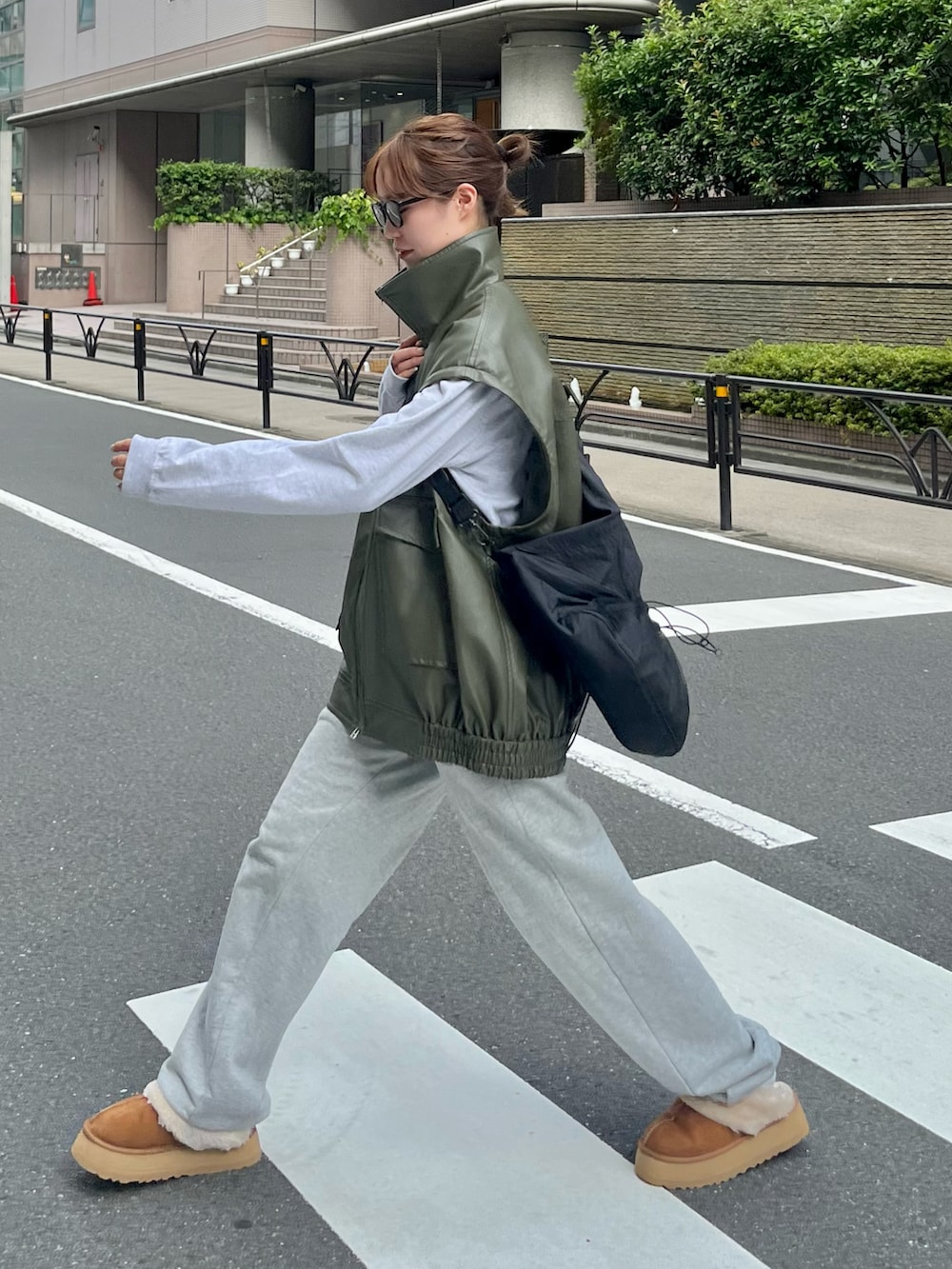 グリーン系のライダースジャケット、グレー系のスウェットパンツ、ブラウン系のサンダルを着用したレディースの秋コーディネートの3枚目の写真