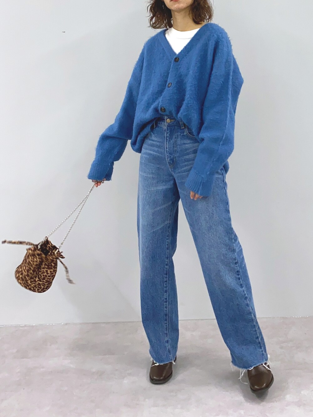 オレンジ系のカーディガン/ボレロ、ブラウン系のショルダーバッグ、ブルー系のデニムパンツを着用したレディースの冬コーディネートの3枚目の写真