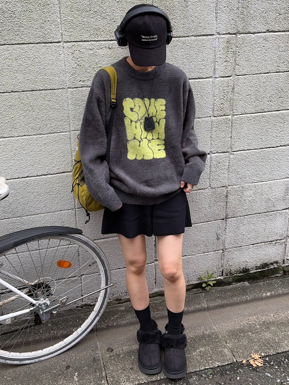 グレー系のニット/セーター、グリーン系のバックパック/リュック、ブラック系のサンダルを着用したレディースの秋コーディネートの4枚目の写真