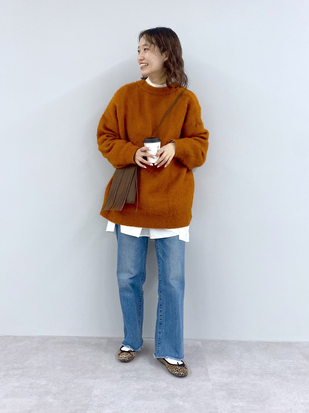 ブルー系のニット/セーター、イエロー系のショルダーバッグ、ブルー系のデニムパンツを着用したレディースの秋コーディネートの3枚目の写真