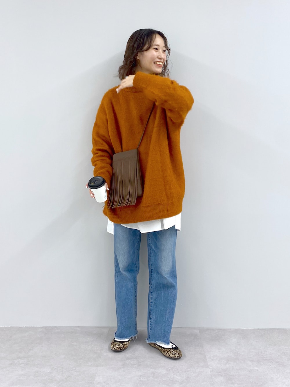 ブルー系のニット/セーター、イエロー系のショルダーバッグ、ブルー系のデニムパンツを着用したレディースの秋コーディネートの4枚目の写真