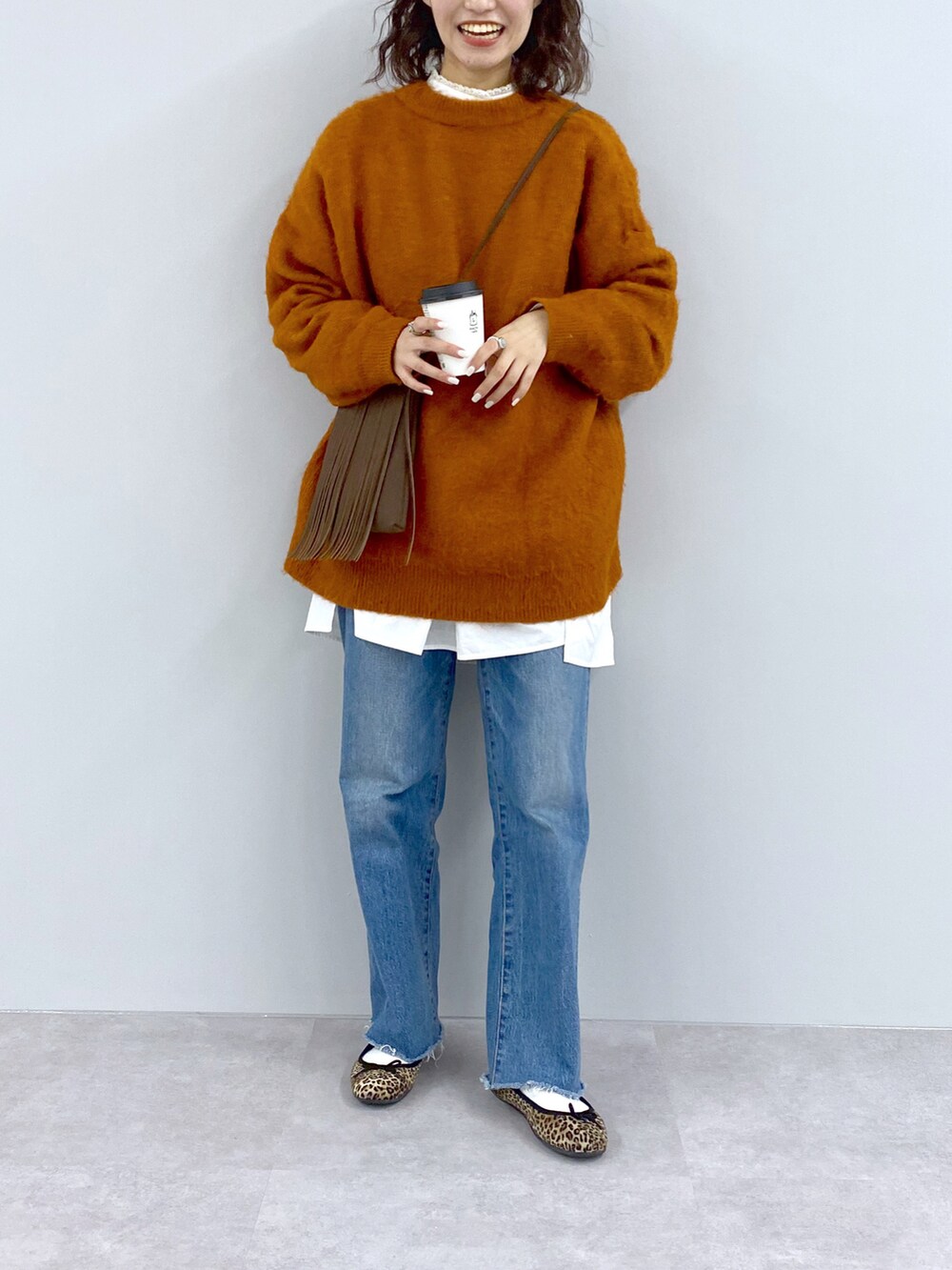 ブルー系のニット/セーター、イエロー系のショルダーバッグ、ブルー系のデニムパンツを着用したレディースの秋コーディネートの2枚目の写真