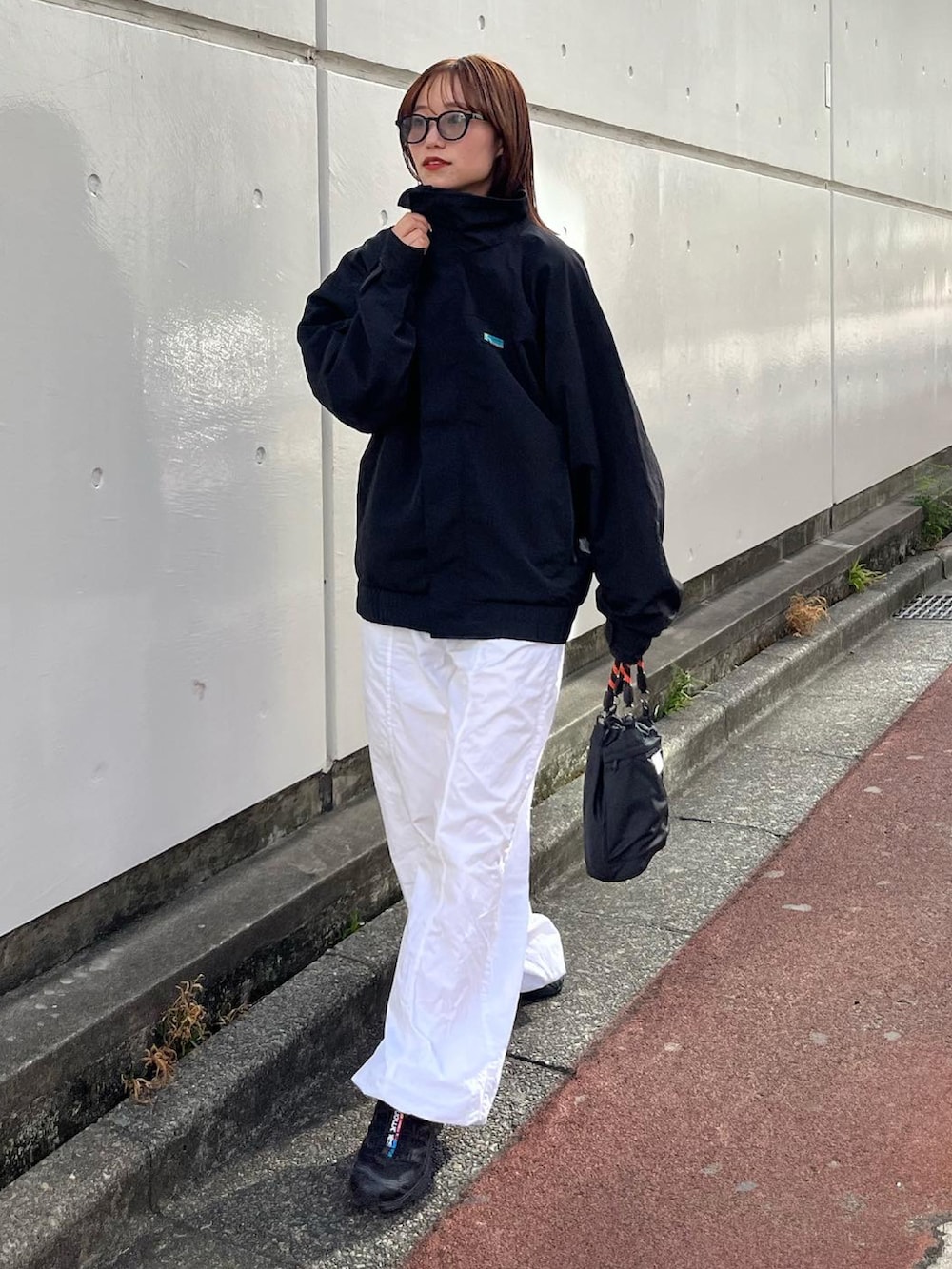 ブラック系のナイロンジャケット、ホワイト系のパンツ、ブラック系のシューズを着用したレディースの秋コーディネートの3枚目の写真