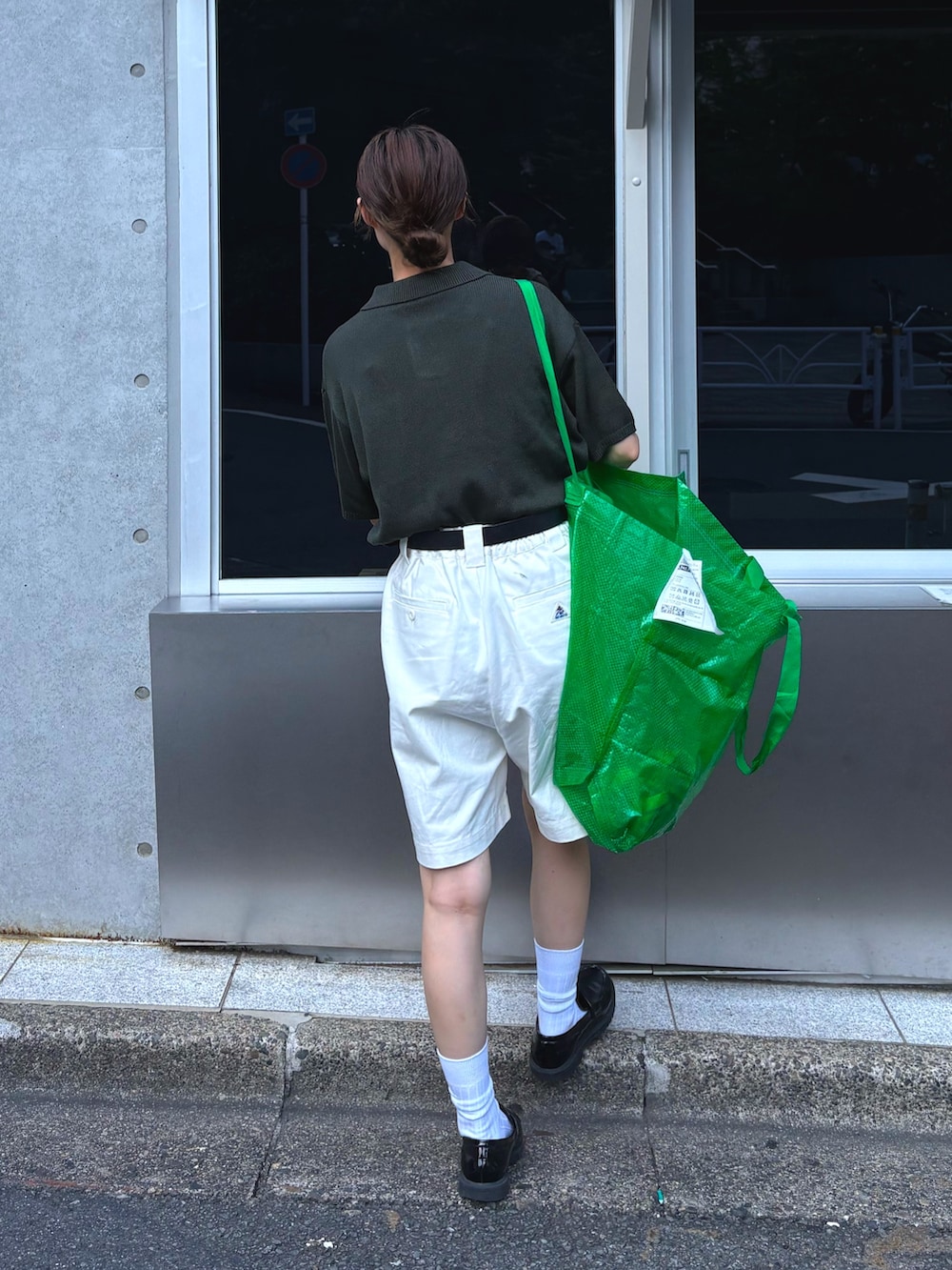 グリーン系のポロシャツ、ホワイト系のデニムパンツを着用したレディースの夏コーディネートの2枚目の写真