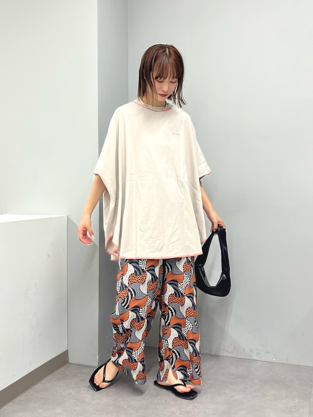 グレー系のTシャツ/カットソー、オレンジ系のその他パンツ、ブラック系のハンドバッグを着用したレディースの夏コーディネートの3枚目の写真