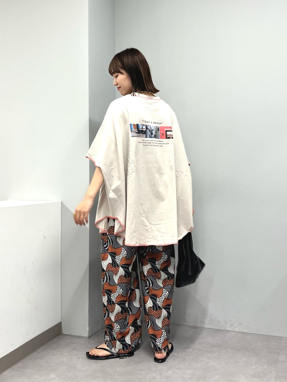 グレー系のTシャツ/カットソー、オレンジ系のその他パンツ、ブラック系のハンドバッグを着用したレディースの夏コーディネートの2枚目の写真