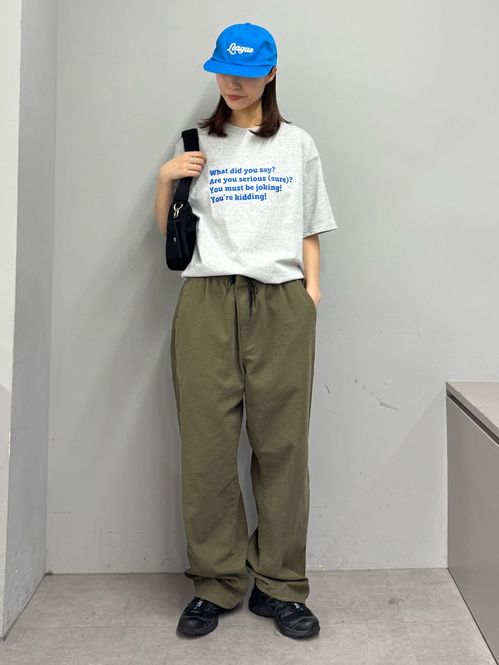 グレー系のTシャツ/カットソー、グリーン系のカーゴパンツ、ブラック系のショルダーバッグを着用したレディースの春コーディネートの2枚目の写真