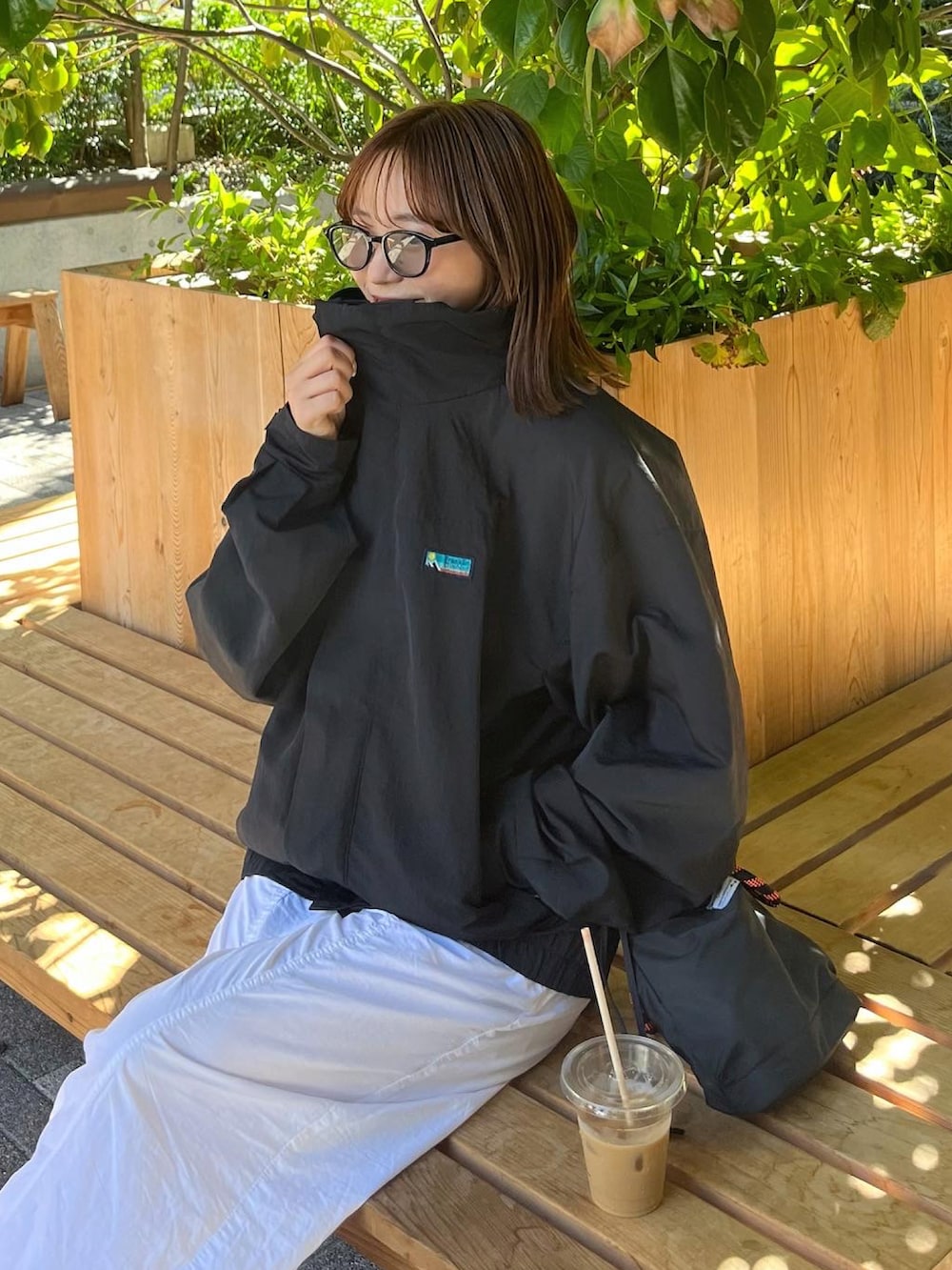 ブラック系のナイロンジャケット、ホワイト系のパンツ、ブラック系のシューズを着用したレディースの秋コーディネートの2枚目の写真