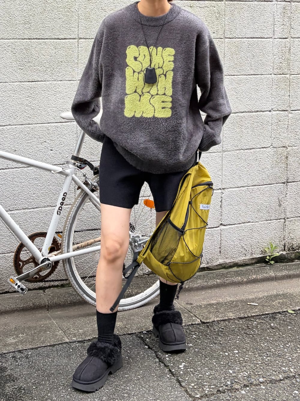グレー系のニット/セーター、グリーン系のバックパック/リュック、ブラック系のサンダルを着用したレディースの秋コーディネートの2枚目の写真