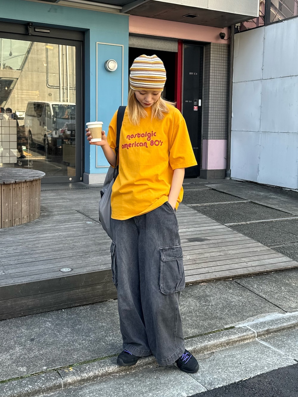 イエロー系のTシャツ/カットソー、ブラック系のカーゴパンツ、ブラック系のバックパック/リュックを着用したレディースの春コーディネートの2枚目の写真