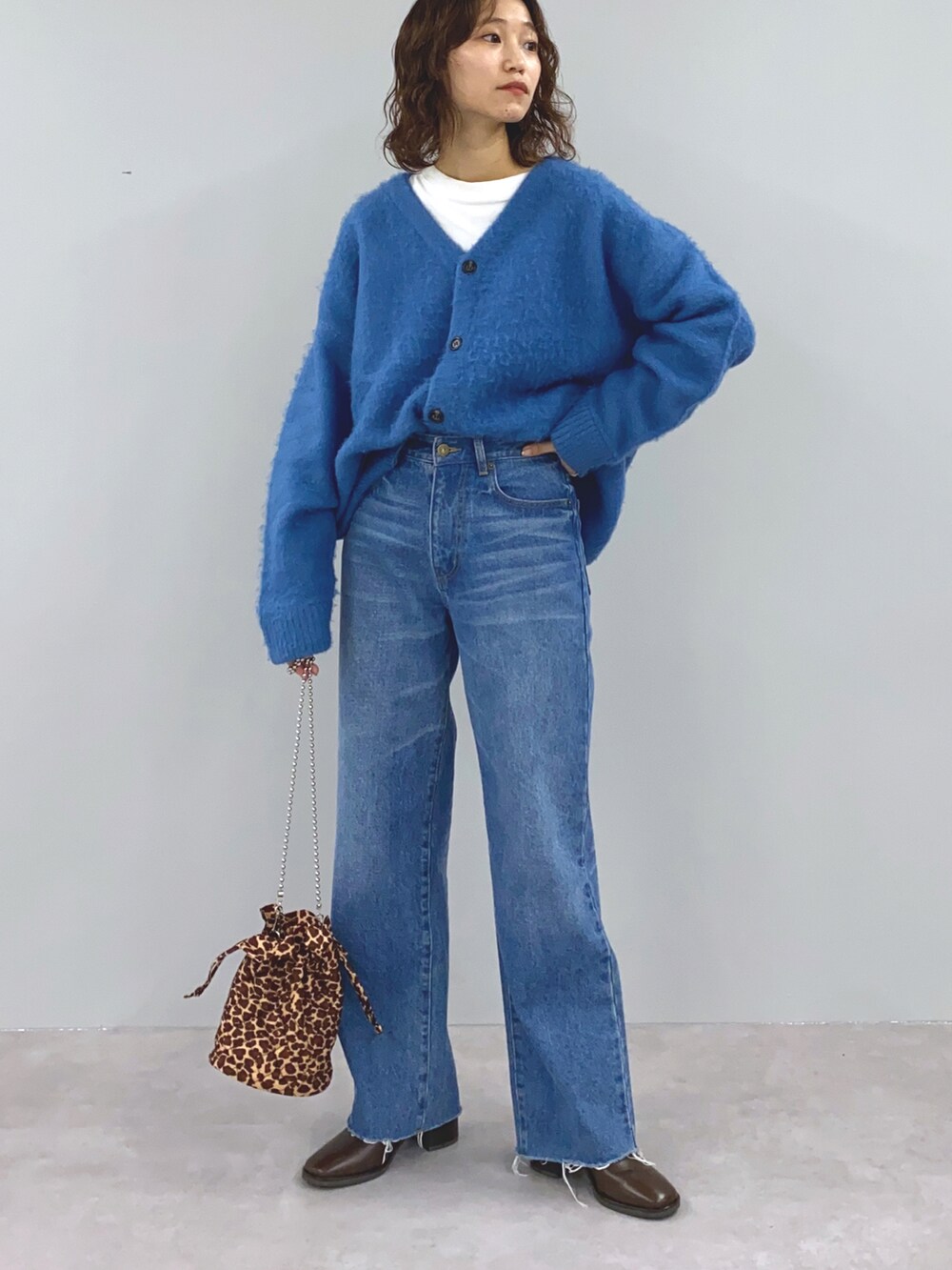 オレンジ系のカーディガン/ボレロ、ブラウン系のショルダーバッグ、ブルー系のデニムパンツを着用したレディースの冬コーディネートの4枚目の写真