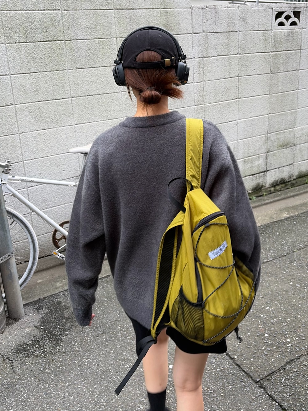 グレー系のニット/セーター、グリーン系のバックパック/リュック、ブラック系のサンダルを着用したレディースの秋コーディネートの3枚目の写真