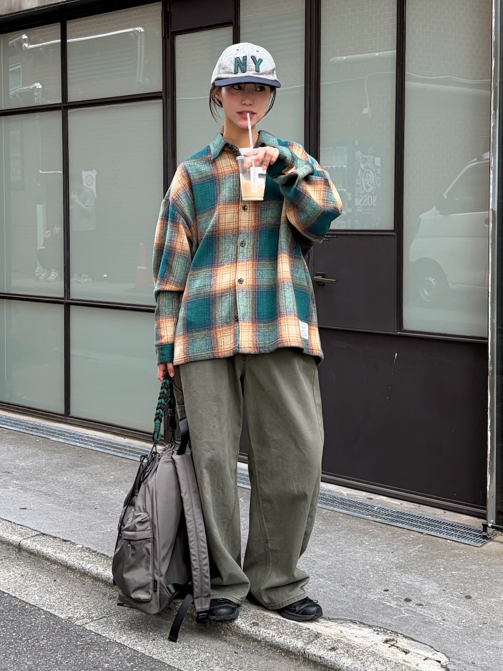 グリーン系のシャツ/ブラウス、グレー系のデニムパンツ、グレー系のバックパック/リュックを着用したレディースの秋コーディネートの3枚目の写真