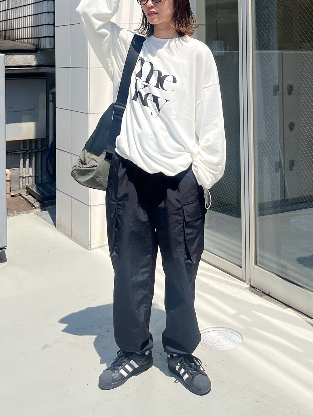 ホワイト系のTシャツ/カットソー、ブラック系のカーゴパンツ、グリーン系のショルダーバッグを着用したレディースの秋コーディネートの2枚目の写真