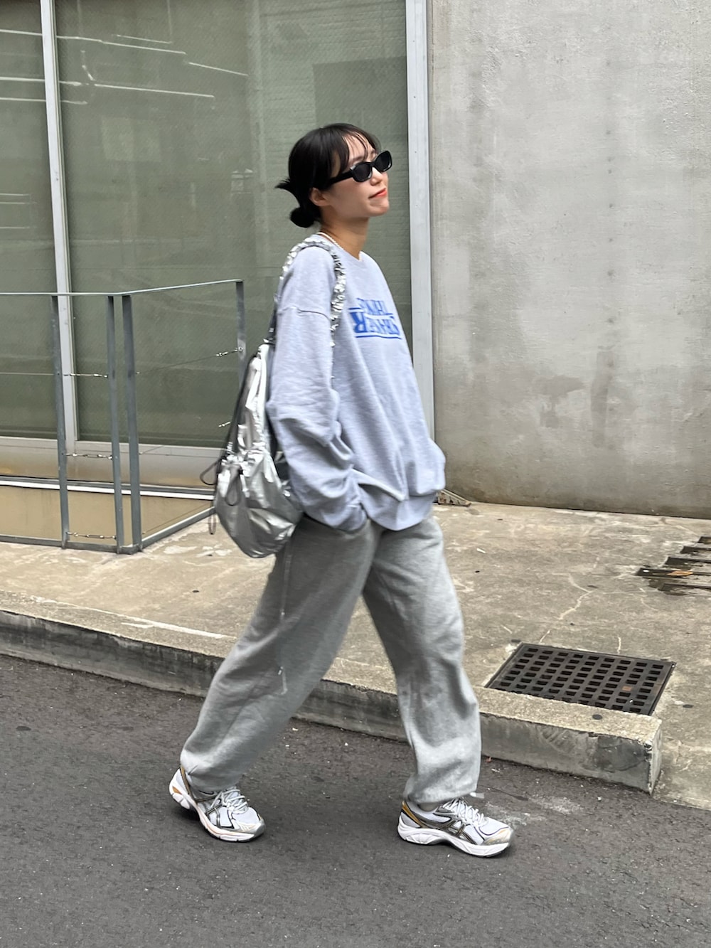 グレー系のスウェット、シルバー系のショルダーバッグ、グレー系のスウェットパンツを着用したレディースの秋コーディネートの2枚目の写真