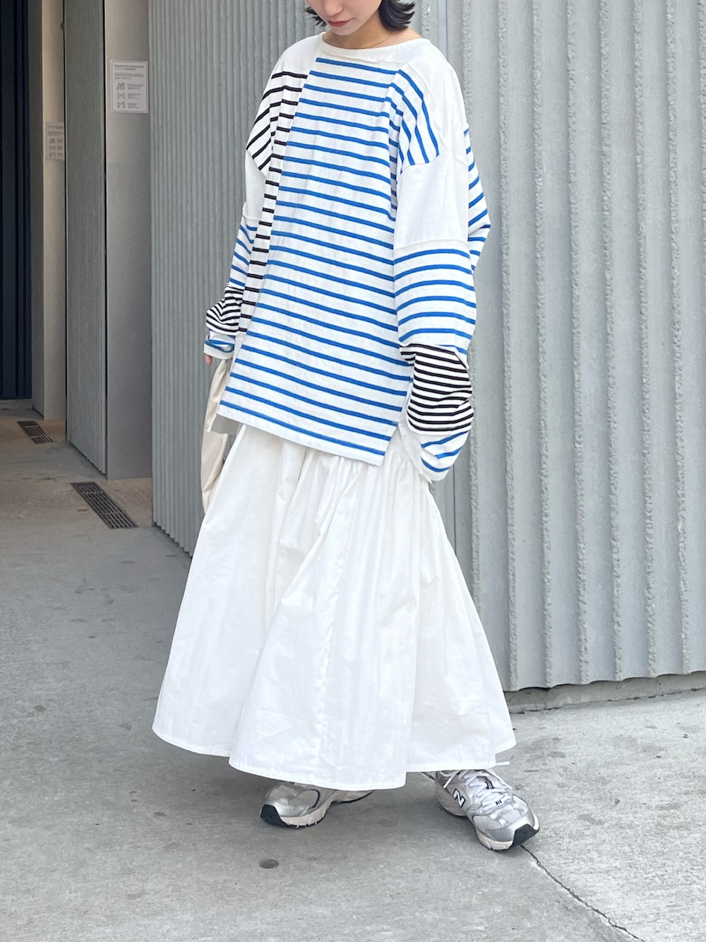 ブルー系のTシャツ/カットソー、ホワイト系のスカート、ホワイト系のハンドバッグを着用したレディースの春コーディネートの2枚目の写真