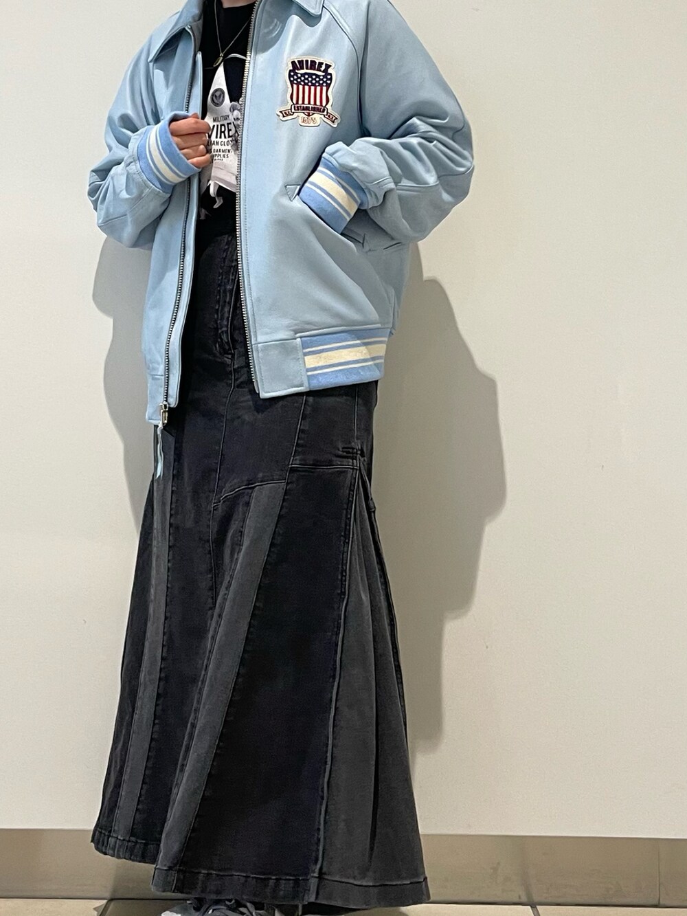 ブルー系のスタジャン、ブラック系のデニムスカート、ホワイト系のTシャツ/カットソーを着用したレディースの秋コーディネートの2枚目の写真