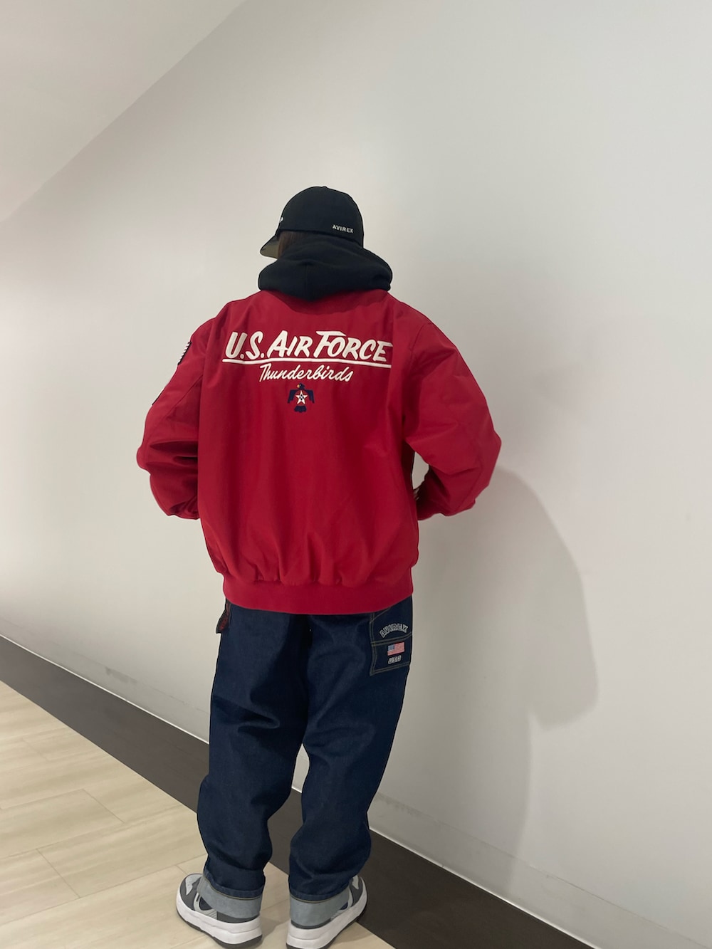 その他のデニムパンツ、レッド系のミリタリージャケット、ブラック系のパーカーを着用したレディースの冬コーディネートの2枚目の写真